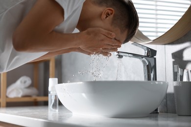 Photo of Man washing his face over sink in bathroom