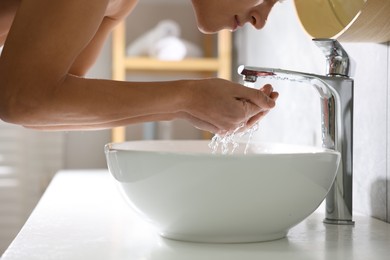 Photo of Man washing his face over sink in bathroom, closeup