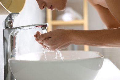 Photo of Man washing his face over sink in bathroom, closeup