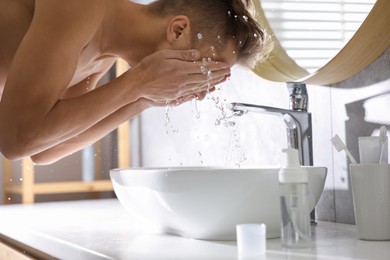 Photo of Man washing his face over sink in bathroom