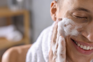 Photo of Man washing his face with cosmetic product in bathroom, closeup. Space for text