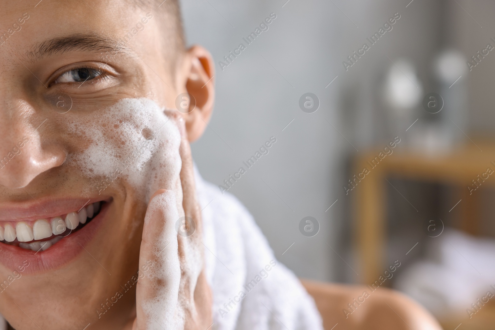 Photo of Man washing his face with cosmetic product in bathroom, closeup. Space for text