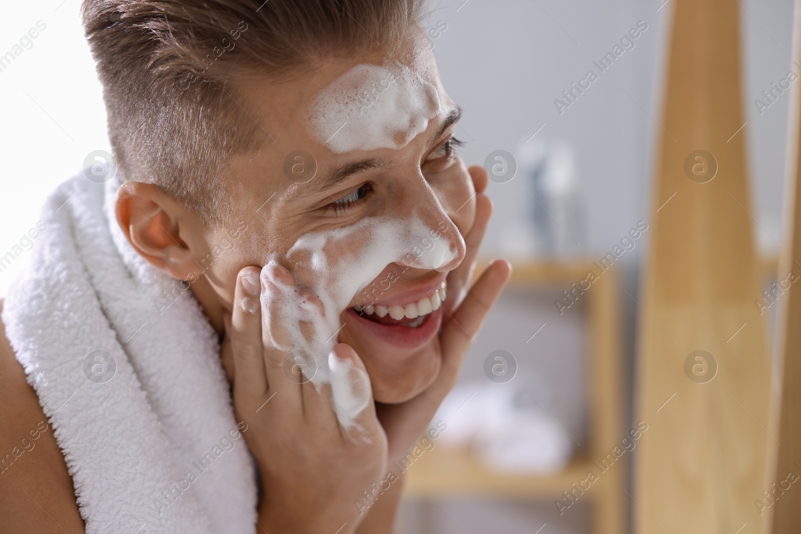 Photo of Man washing his face with cosmetic product in bathroom, space for text