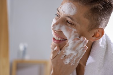 Photo of Man washing his face with cosmetic product in bathroom, space for text