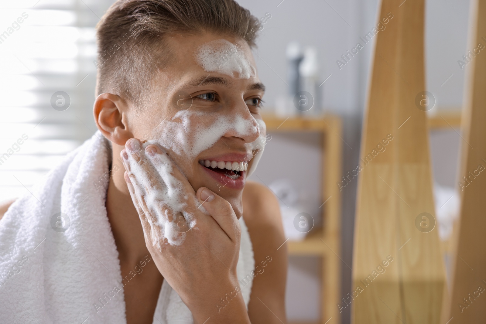 Photo of Man washing his face with cosmetic product in bathroom, space for text