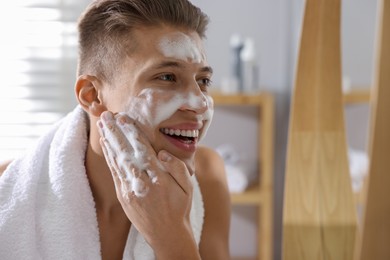 Photo of Man washing his face with cosmetic product in bathroom, space for text