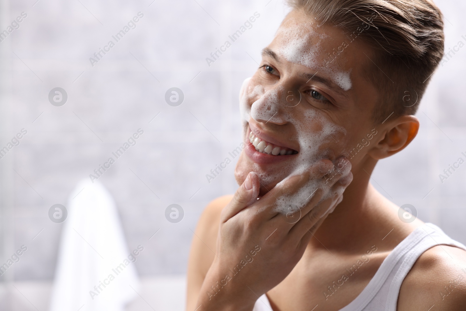 Photo of Man washing his face with cosmetic product in bathroom, space for text