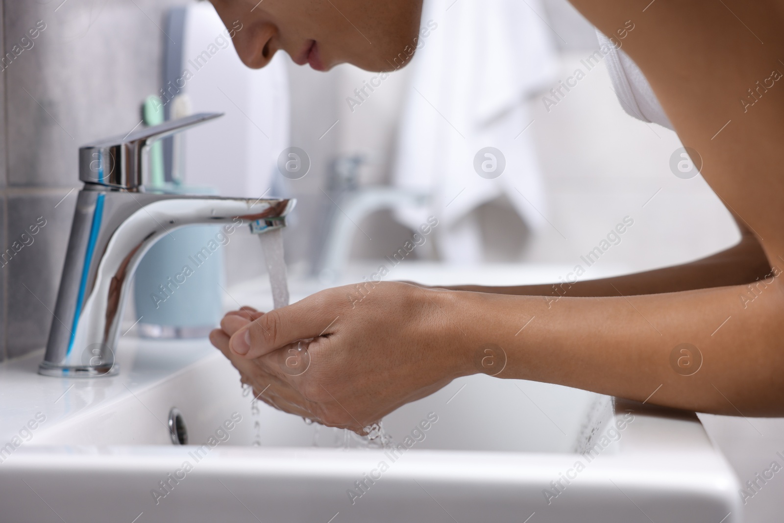 Photo of Man washing his face over sink in bathroom, closeup