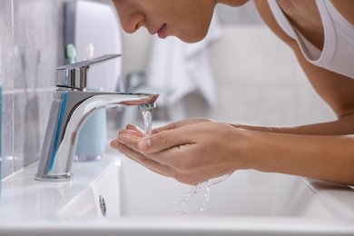 Photo of Man washing his face over sink in bathroom, closeup