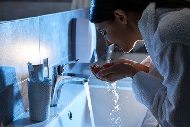 Photo of Woman washing her face over sink in bathroom