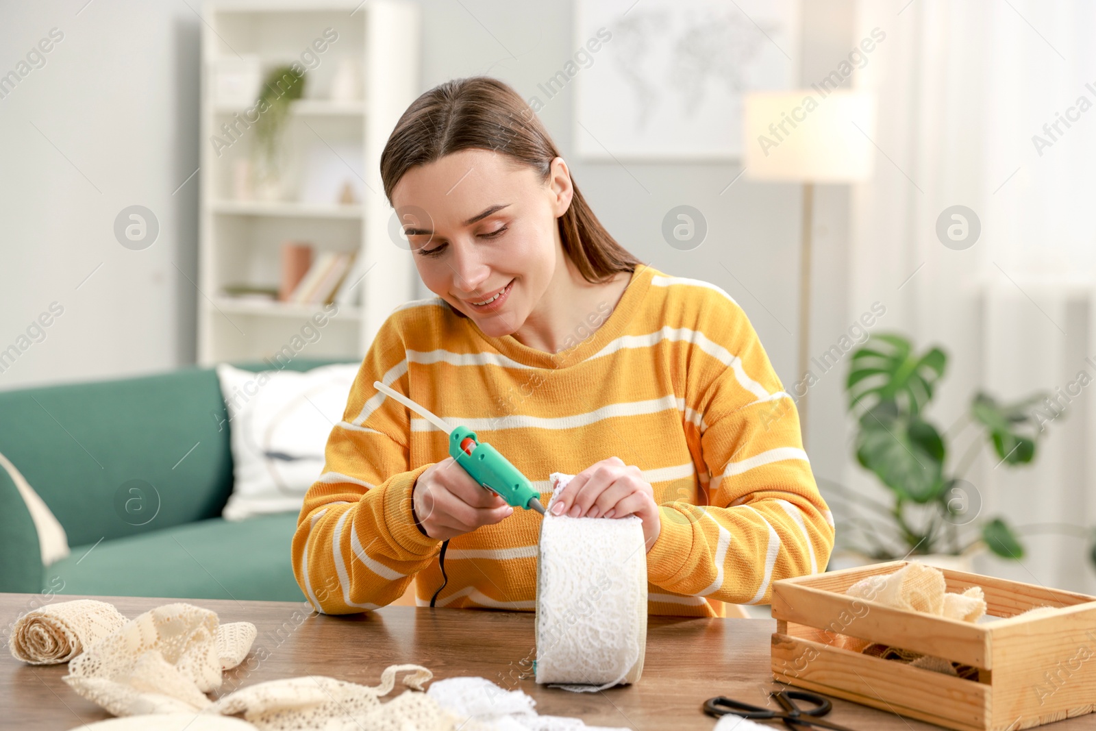 Photo of Woman with hot glue gun making craft at table indoors