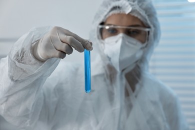 Photo of Scientist holding test tube with blue sample in laboratory, selective focus