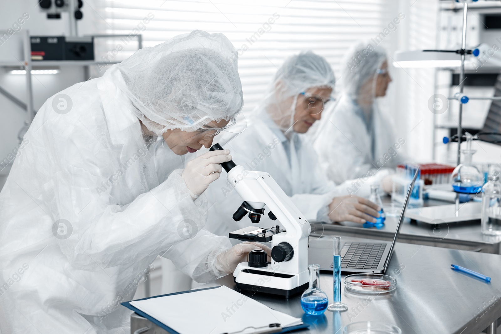 Photo of Scientist working with microscope at table in laboratory