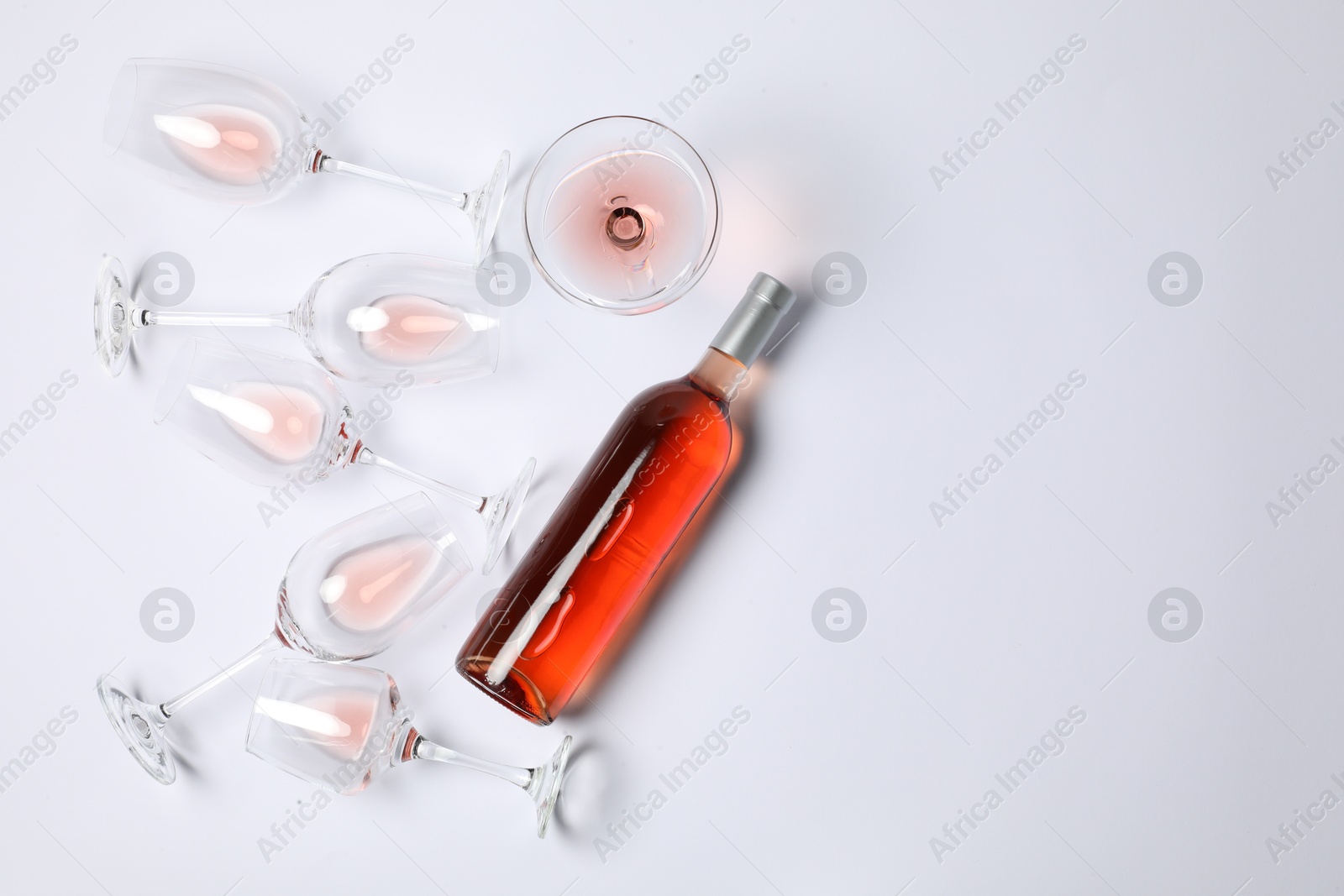 Photo of Bottle of delicious rose wine and glasses on white background, flat lay. Space for text