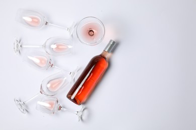 Photo of Bottle of delicious rose wine and glasses on white background, flat lay. Space for text