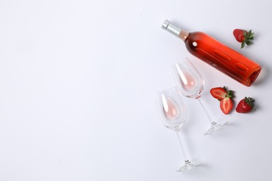 Photo of Bottle of rose wine, glasses and strawberries on white background, flat lay. Space for text