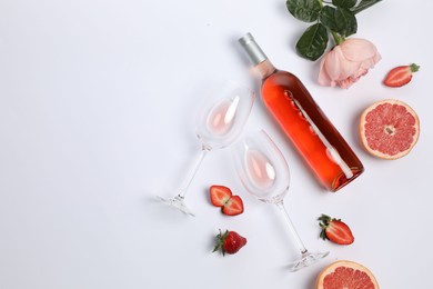 Flat lay composition with rose wine and fruits on white background. Space for text