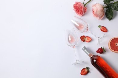 Flat lay composition with rose wine and fruits on white background. Space for text