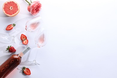 Flat lay composition with rose wine and fruits on white background. Space for text