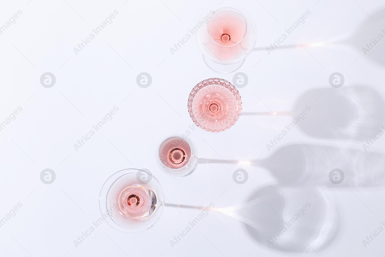 Photo of Delicious rose wine in glasses on white background, flat lay