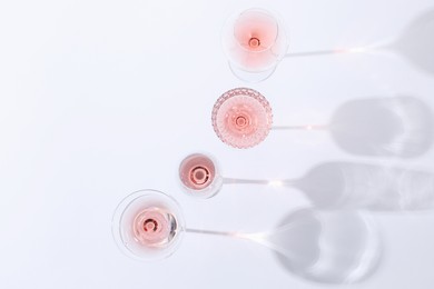 Photo of Delicious rose wine in glasses on white background, flat lay