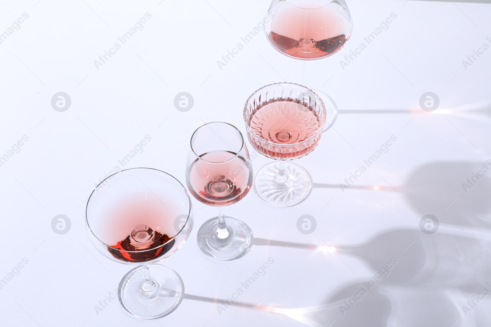 Photo of Tasty rose wine in glasses on white background