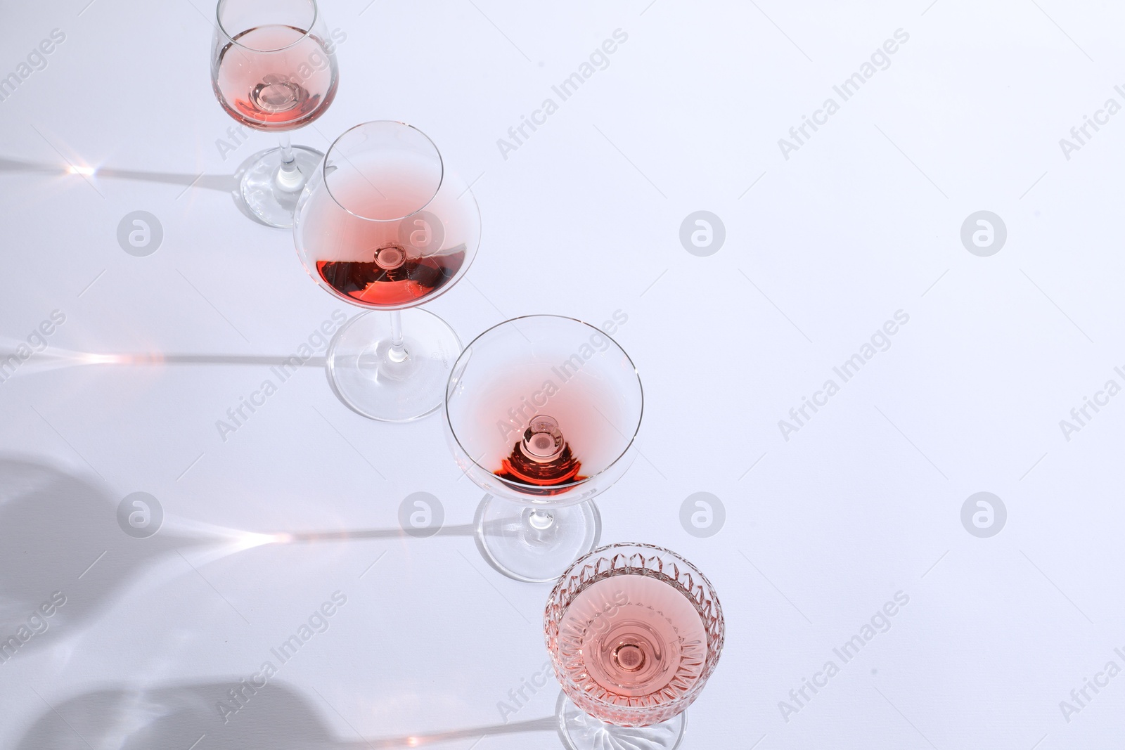 Photo of Tasty rose wine in glasses on white background. Space for text