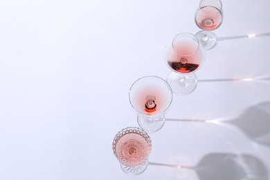 Photo of Tasty rose wine in glasses on white background. Space for text