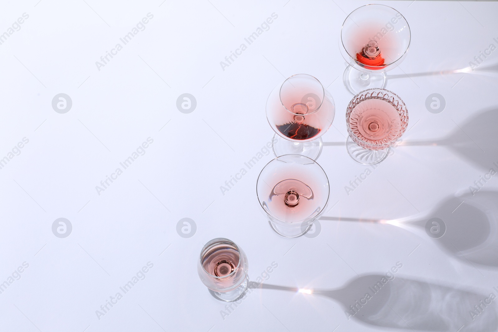 Photo of Delicious rose wine in glasses on white background, above view. Space for text