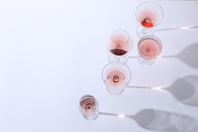 Delicious rose wine in glasses on white background, above view. Space for text