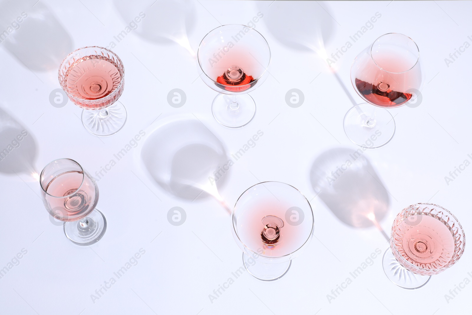 Photo of Delicious rose wine in glasses on white background, above view