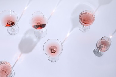 Photo of Delicious rose wine in glasses on white background, above view