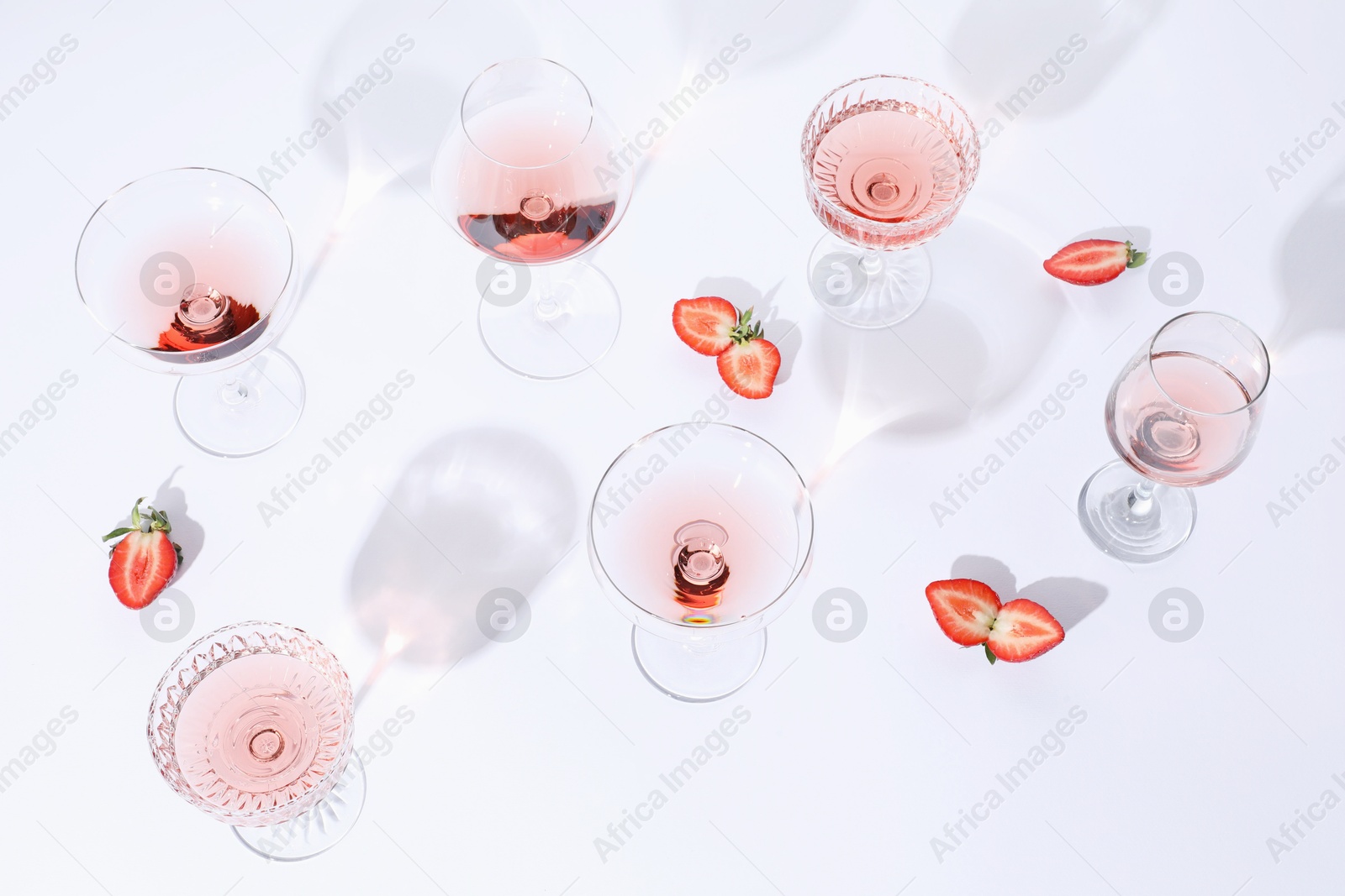 Photo of Tasty rose wine in glasses and fresh strawberries on white background, above view