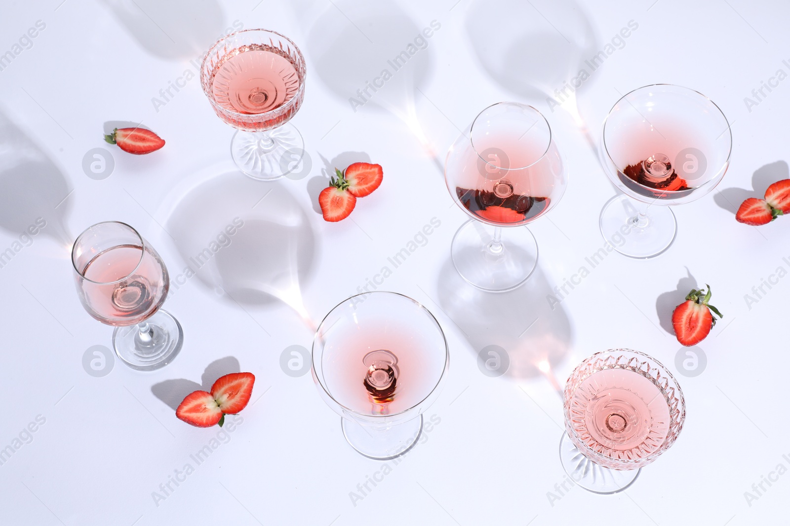 Photo of Tasty rose wine in glasses and fresh strawberries on white background, above view