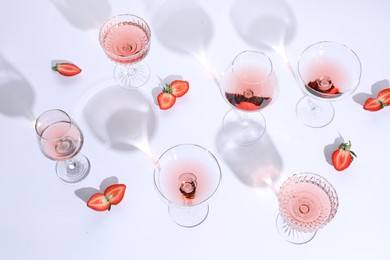 Tasty rose wine in glasses and fresh strawberries on white background, above view