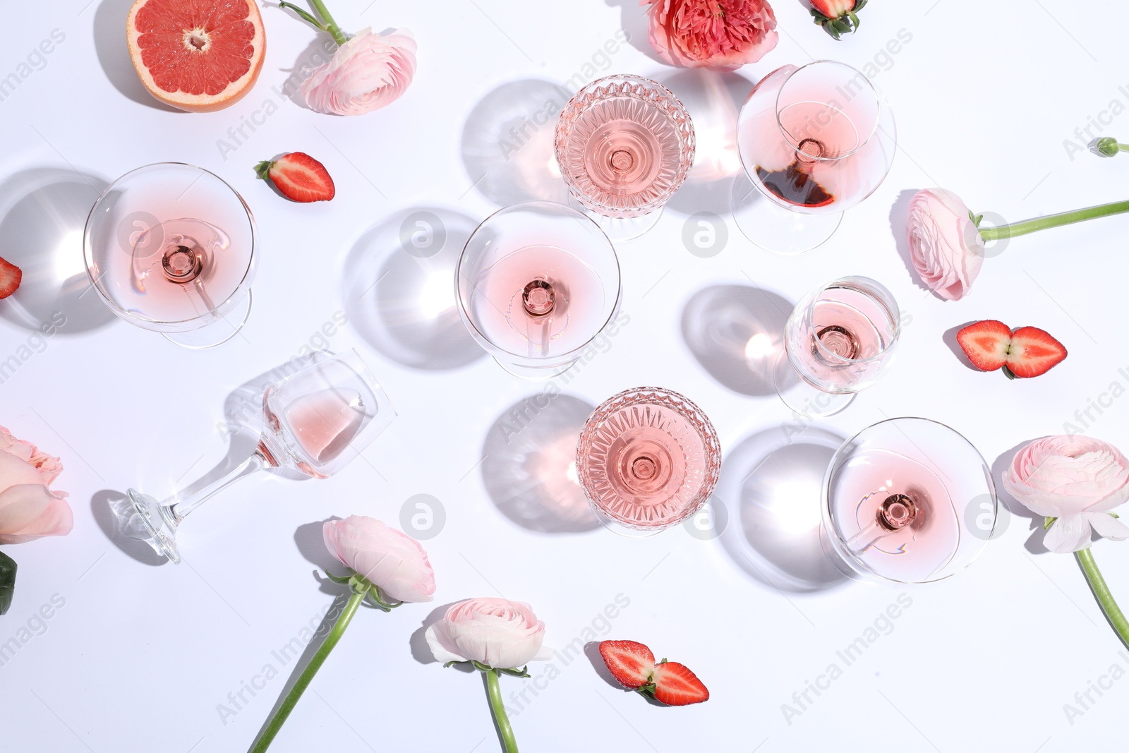 Photo of Flat lay composition with rose wine in glasses and flowers on white background