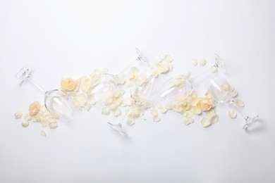 Photo of Flat lay composition with wineglasses and rose petals on white background