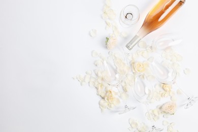 Photo of Flat lay composition with rose wine, glasses and petals on white background. Space for text