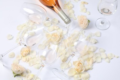 Photo of Composition with rose wine, glasses and petals on white background