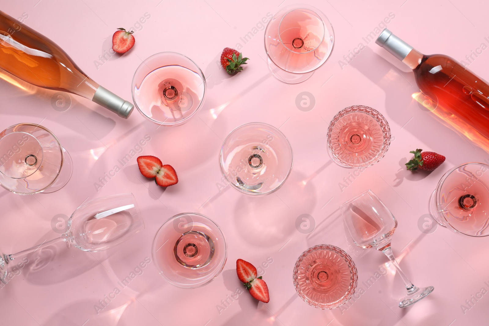 Photo of Flat lay composition with tasty rose wine and strawberries on pink background