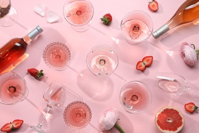 Flat lay composition with tasty rose wine and strawberries on pink background