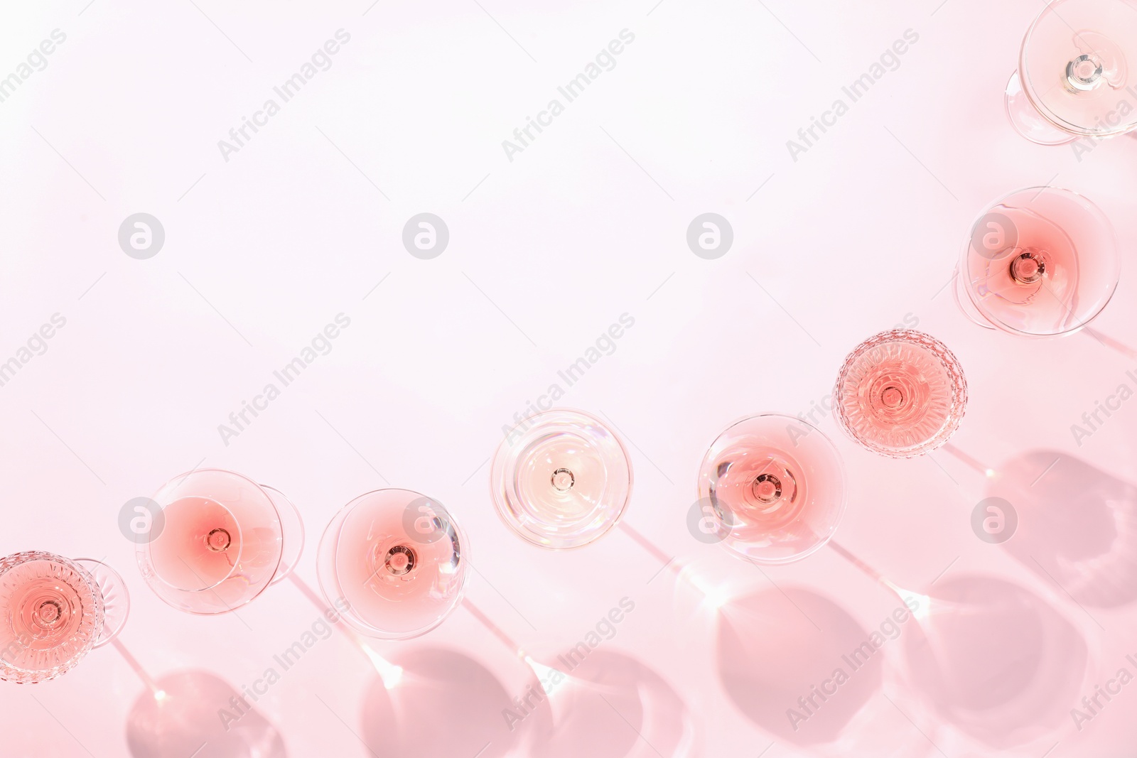 Photo of Tasty rose wine in glasses on pink background, flat lay. Space for text