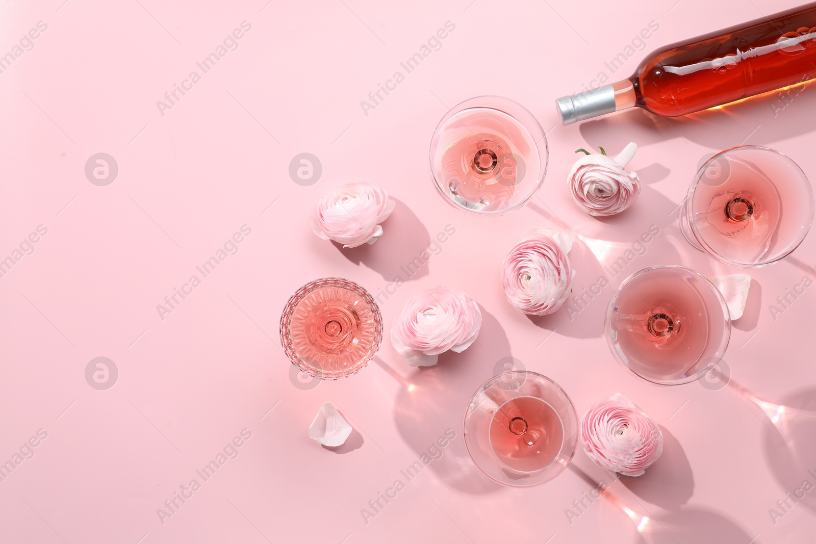 Photo of Flat lay composition with delicious rose wine and flowers on pink background. Space for text