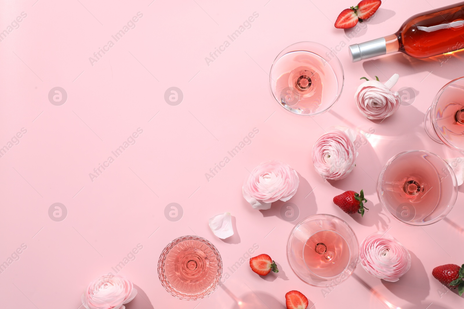 Photo of Flat lay composition with delicious rose wine and flowers on pink background. Space for text