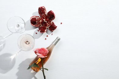 Flat lay composition with delicious rose wine and pomegranate on white background. Space for text