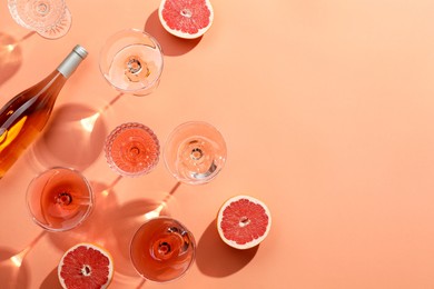 Photo of Flat lay composition with delicious rose wine and grapefruits on coral color background. Space for text