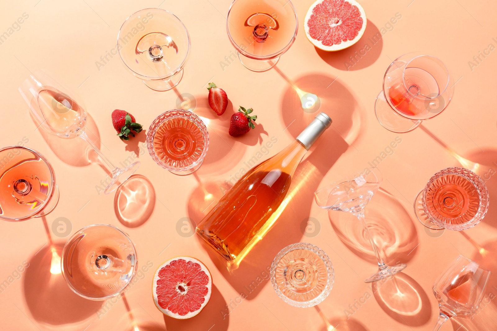 Photo of Flat lay composition with delicious rose wine on coral color background