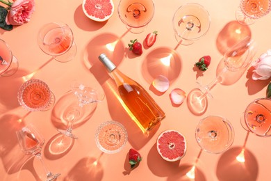 Photo of Flat lay composition with delicious rose wine on coral color background