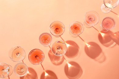 Tasty rose wine in glasses on coral color background, flat lay