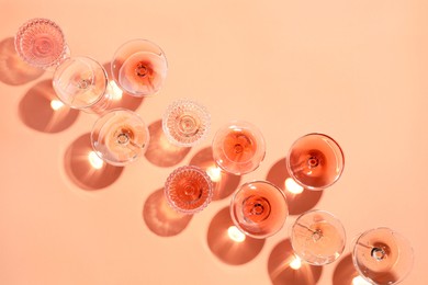 Tasty rose wine in glasses on coral color background, flat lay